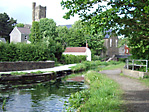 Photo of sunny day alongside the Clydach stretch of Swansea Canal with St. Mary's Church towering in the distance.